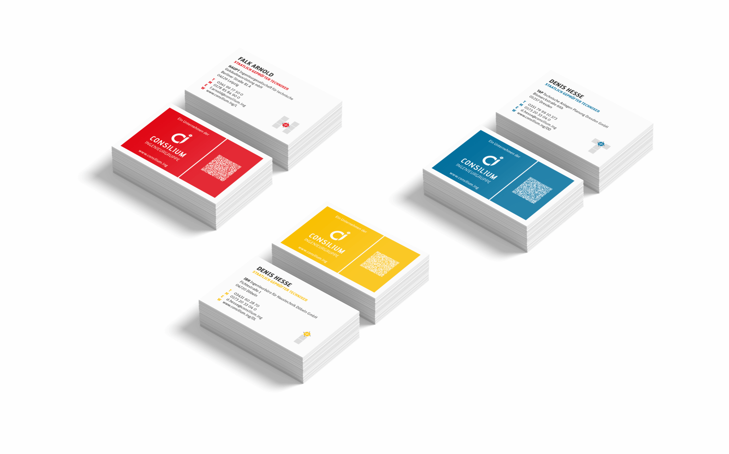 Vier Stapel Visitenkarten in rotem, gelbem und blauem Design sind auf weißem Hintergrund angeordnet, wobei jeder Stapel ein anderes Layout und andere Kontaktinformationen aufweist.