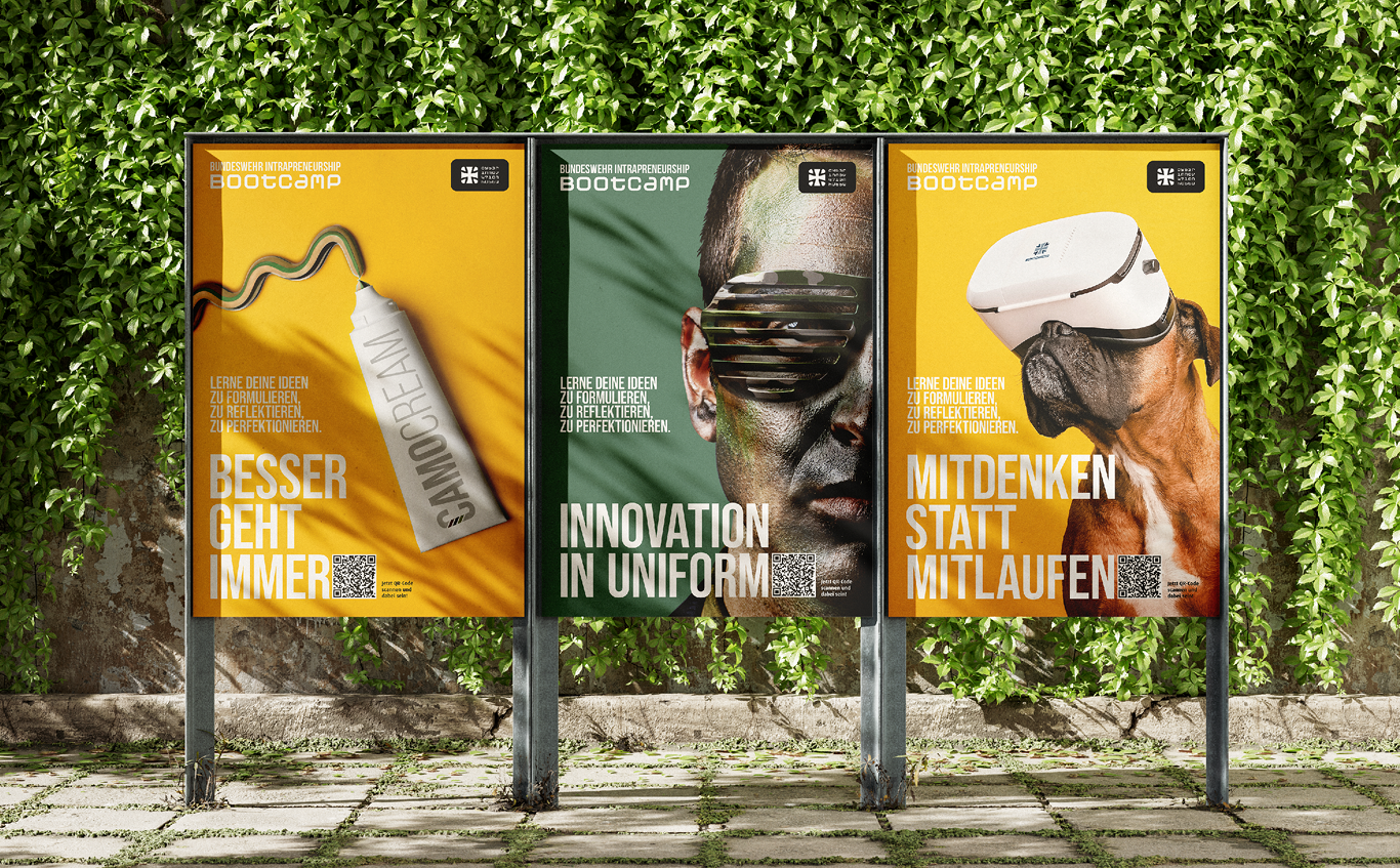 Vor einer grünen Wand stehen drei Plakate, die mit deutschem Text für ein Bootcamp von Geithe & Ußner Hygienefachhandel werben: eine Cremetube, ein Männergesicht mit Tarnfarbe und Gadgets und ein Hund, der ein VR-Headset trägt.